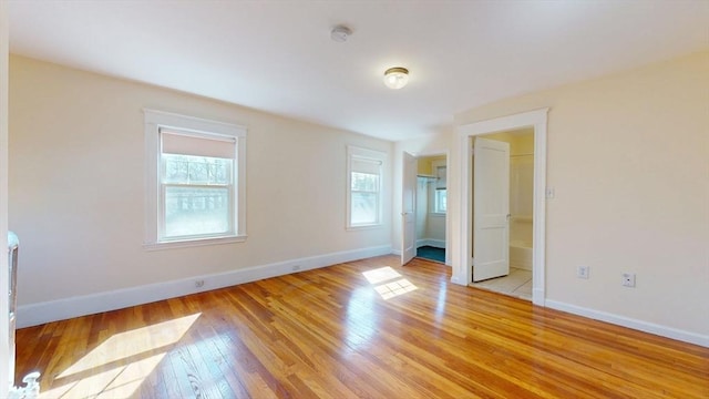 unfurnished bedroom featuring a spacious closet, baseboards, and light wood finished floors