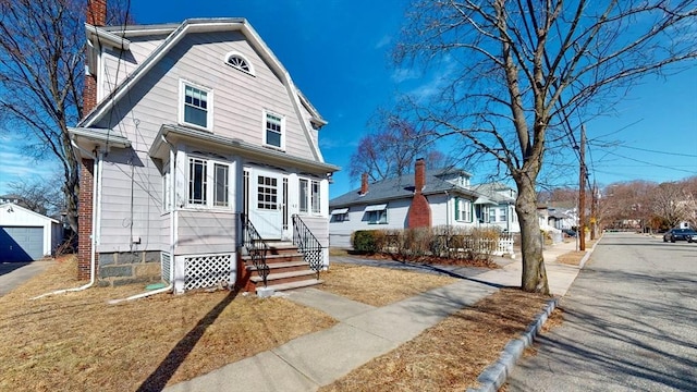 view of front of home with a residential view, a gambrel roof, entry steps, a chimney, and an outdoor structure