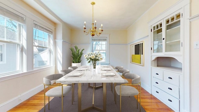 dining room with an inviting chandelier, baseboards, and light wood-type flooring