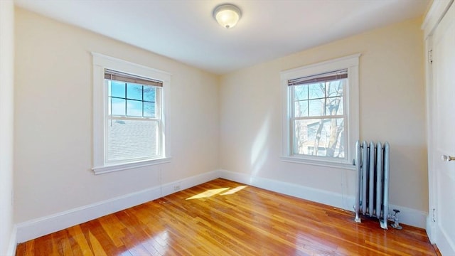 spare room featuring light wood finished floors, plenty of natural light, radiator heating unit, and baseboards