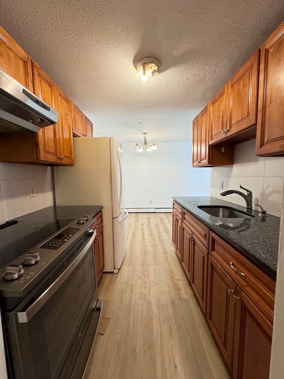 kitchen with light wood-type flooring, sink, tasteful backsplash, stainless steel range with electric stovetop, and dark stone counters