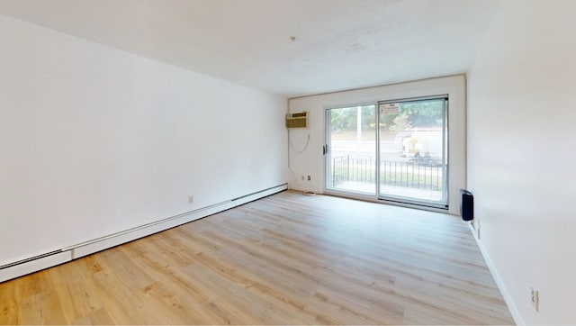 empty room featuring a baseboard heating unit, light hardwood / wood-style floors, and a wall mounted air conditioner