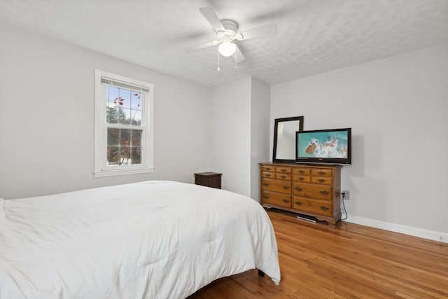 bedroom featuring ceiling fan, hardwood / wood-style flooring, and a textured ceiling