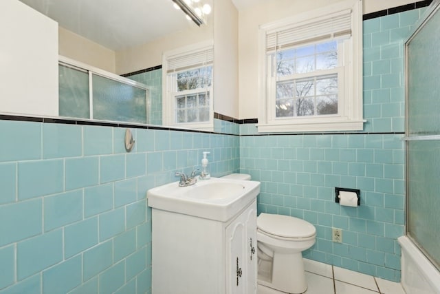 bathroom featuring tile patterned floors, toilet, vanity, and tile walls