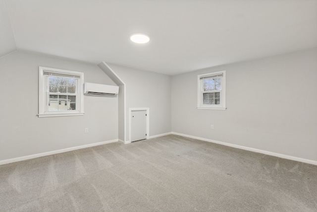 additional living space with lofted ceiling, a wall mounted AC, and light carpet