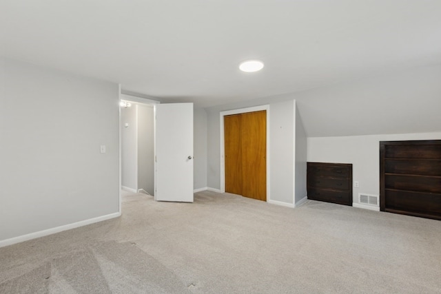 additional living space featuring light colored carpet and vaulted ceiling