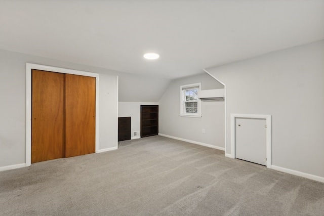 additional living space featuring lofted ceiling, a wall mounted AC, and light colored carpet