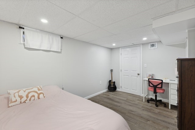 bedroom featuring a drop ceiling and wood-type flooring