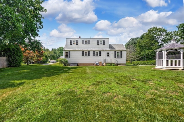 rear view of house featuring a gazebo and a yard