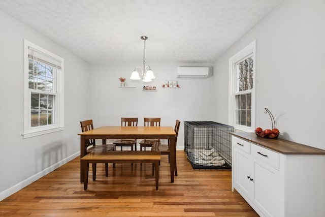 dining room with a wall mounted air conditioner, a notable chandelier, a textured ceiling, and light wood-type flooring