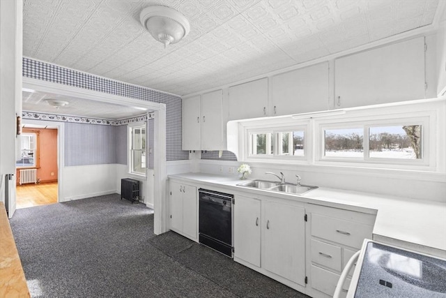 kitchen with sink, radiator heating unit, white cabinetry, and black dishwasher