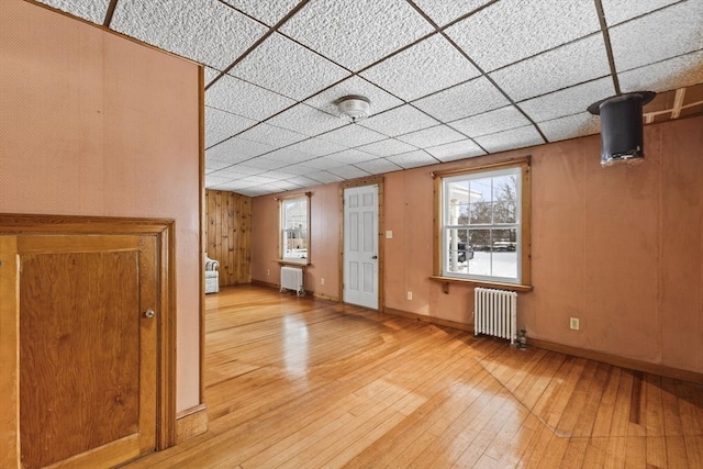 interior space featuring a drop ceiling, radiator, and light hardwood / wood-style flooring