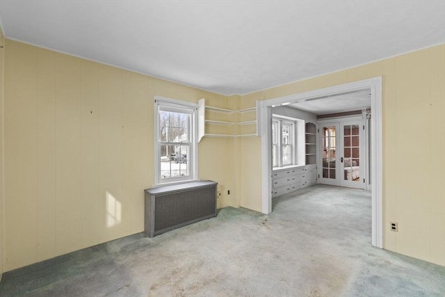 carpeted spare room with radiator heating unit and french doors