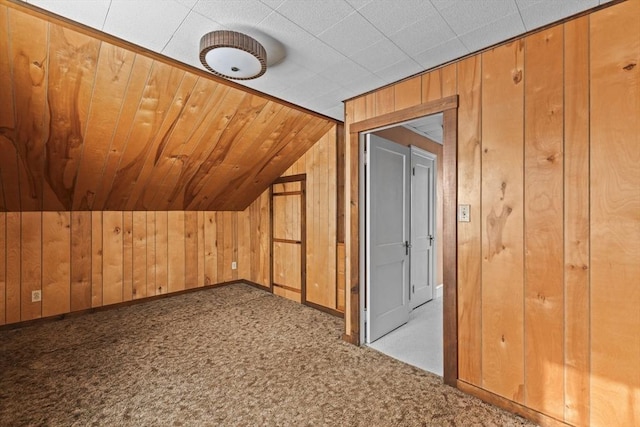 additional living space featuring wood walls, carpet flooring, and vaulted ceiling