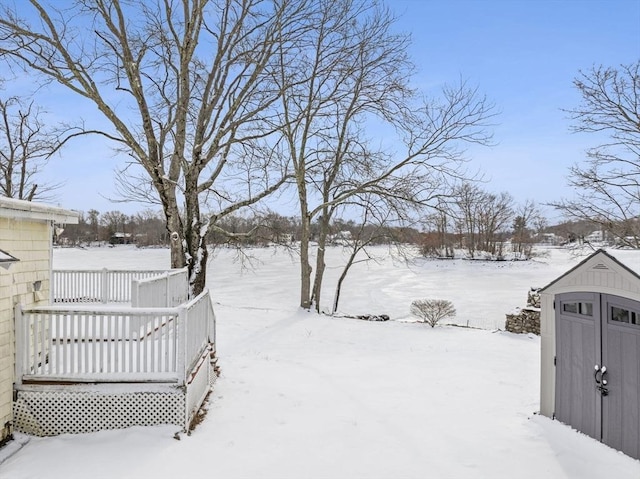 yard covered in snow featuring a wooden deck and a shed