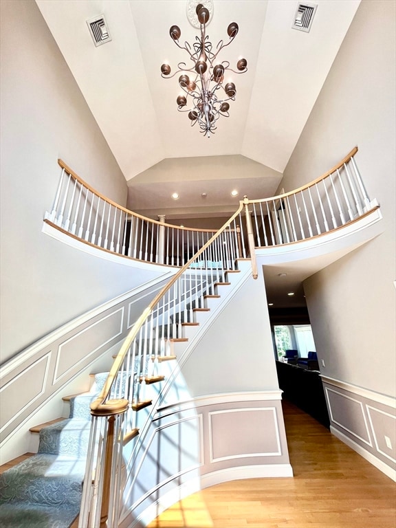 stairway featuring a high ceiling, an inviting chandelier, and hardwood / wood-style floors