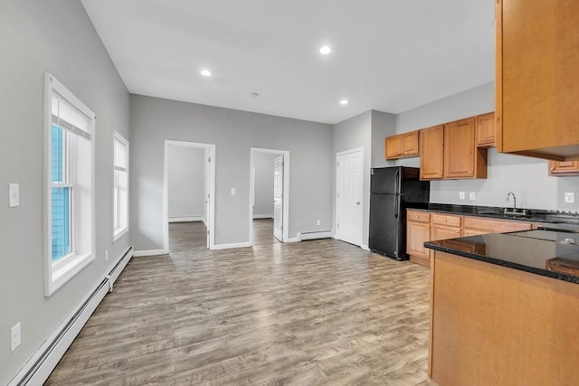 kitchen with a baseboard heating unit, a sink, baseboard heating, freestanding refrigerator, and dark countertops