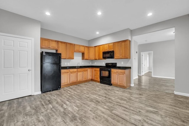 kitchen featuring black appliances, light wood finished floors, dark countertops, and recessed lighting