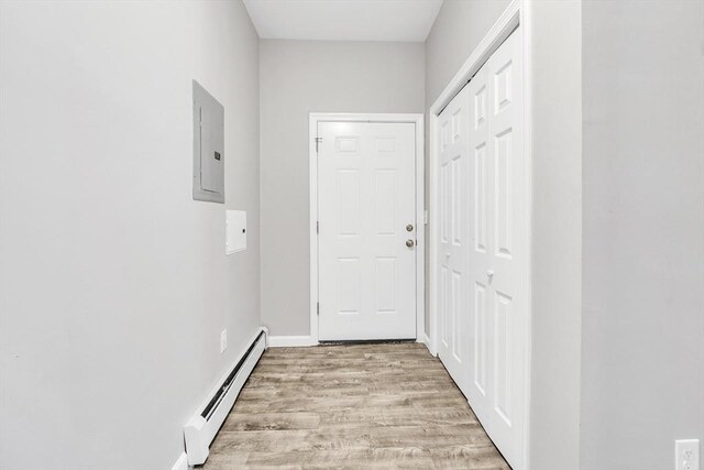 entryway featuring light wood-type flooring, a baseboard radiator, electric panel, and baseboards