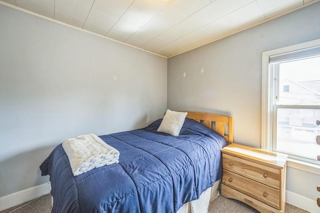 carpeted bedroom featuring ornamental molding and baseboards