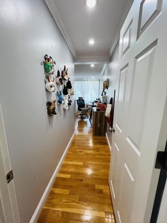 hallway with crown molding, light wood-style floors, and baseboards