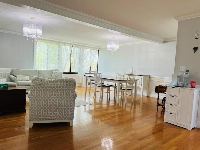 dining space featuring a notable chandelier, ornamental molding, wood finished floors, and a decorative wall