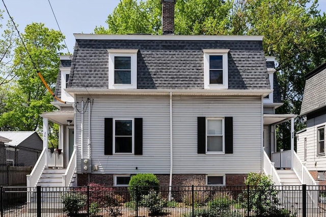 view of front facade featuring stairs, roof with shingles, and a chimney