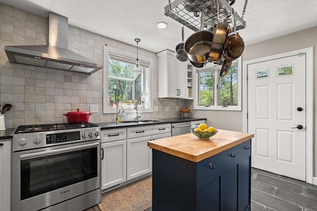 kitchen featuring appliances with stainless steel finishes, wall chimney exhaust hood, wood counters, a sink, and white cabinets
