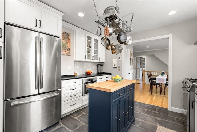 kitchen featuring stainless steel appliances, blue cabinets, butcher block countertops, recessed lighting, and white cabinets