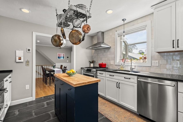 kitchen featuring dishwasher, wall chimney range hood, a sink, butcher block countertops, and backsplash