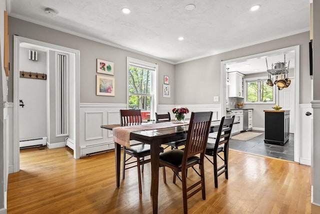 dining space featuring healthy amount of natural light, ornamental molding, wood finished floors, a wainscoted wall, and recessed lighting