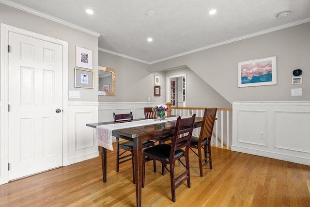 dining space with light wood-style floors, recessed lighting, a decorative wall, and a wainscoted wall