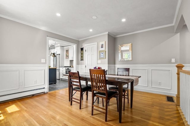 dining area with a wainscoted wall, a baseboard radiator, crown molding, recessed lighting, and wood finished floors