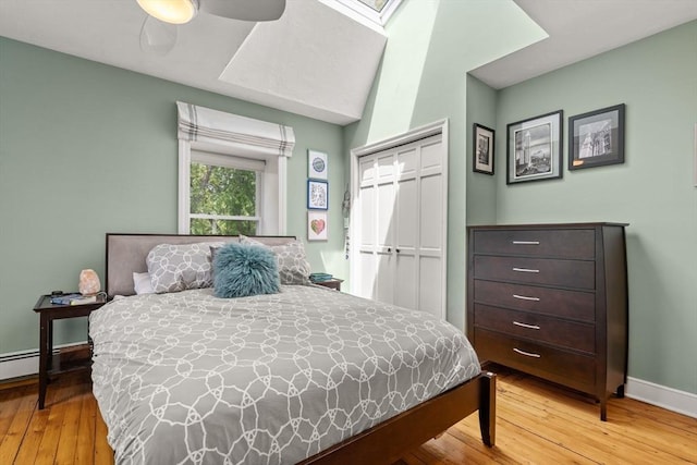bedroom with a closet, hardwood / wood-style floors, baseboards, a ceiling fan, and a skylight