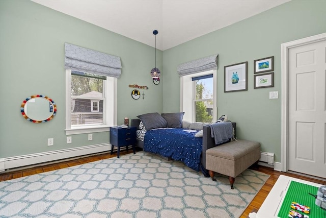 bedroom with multiple windows, wood finished floors, a baseboard radiator, and baseboards