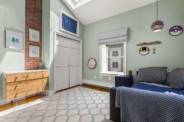 bedroom featuring a baseboard radiator, a skylight, wood finished floors, vaulted ceiling, and a closet