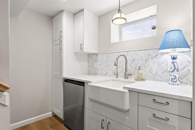 kitchen with tasteful backsplash, wood finished floors, light countertops, a sink, and baseboards
