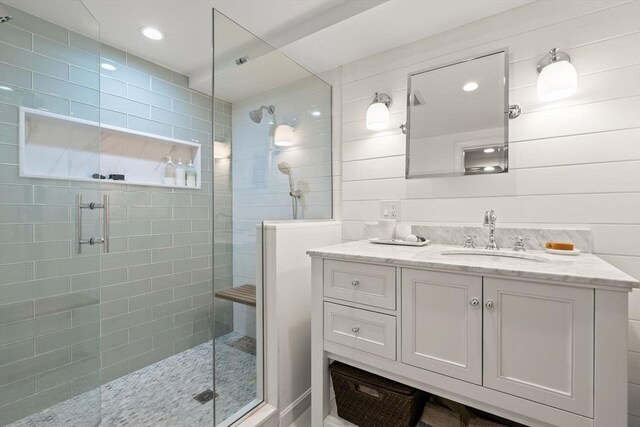 full bath with tiled shower, vanity, and recessed lighting