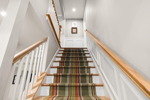 stairs with a decorative wall, a wainscoted wall, and recessed lighting