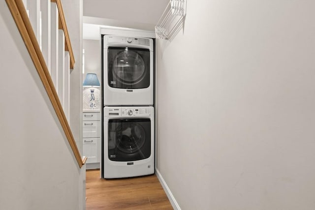 laundry area featuring estacked washer and dryer, light wood finished floors, and baseboards