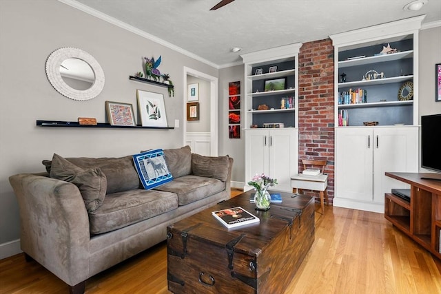 living room featuring light wood-style floors, ceiling fan, crown molding, and built in shelves