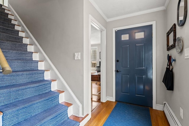 entryway with a baseboard radiator, wood finished floors, stairs, baseboards, and crown molding