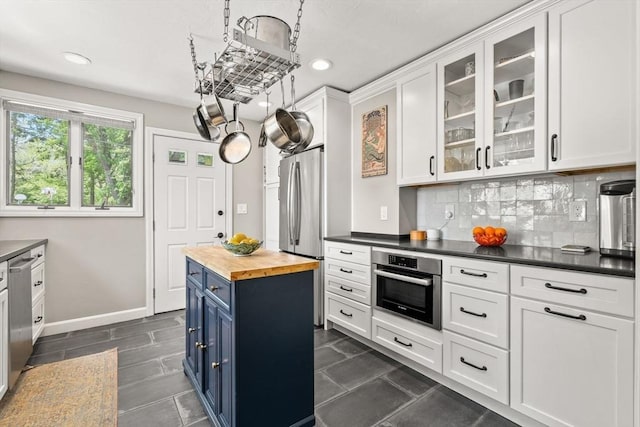 kitchen featuring appliances with stainless steel finishes, blue cabinetry, wood counters, recessed lighting, and white cabinetry