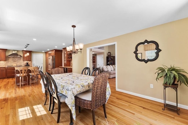 dining area with baseboards, recessed lighting, light wood-style flooring, and a chandelier