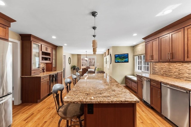kitchen featuring decorative backsplash, a breakfast bar area, a center island, light wood finished floors, and appliances with stainless steel finishes