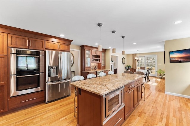 kitchen with appliances with stainless steel finishes, light wood-type flooring, and a kitchen bar