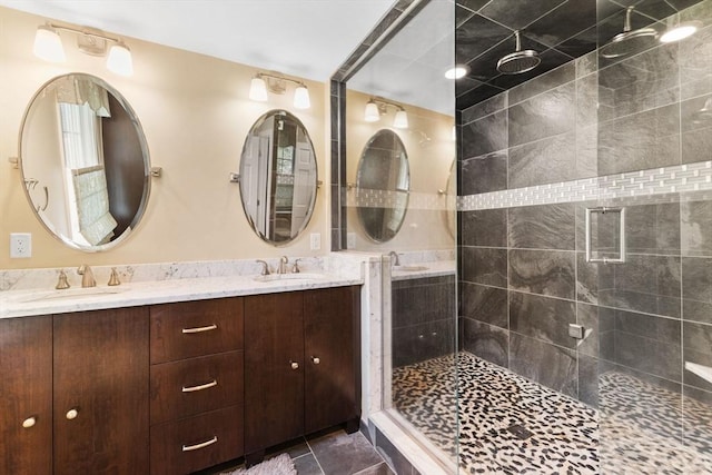 bathroom featuring double vanity, a shower stall, a sink, and tile patterned flooring