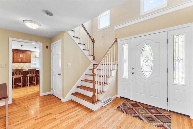 foyer with stairs, baseboards, and light wood-type flooring
