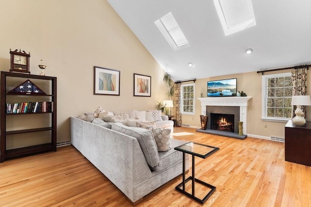 living area with a skylight, light wood finished floors, a wealth of natural light, and high vaulted ceiling