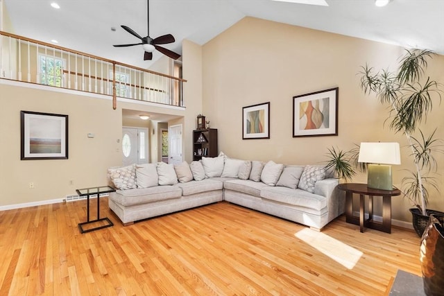 living area featuring baseboards, ceiling fan, high vaulted ceiling, and wood finished floors